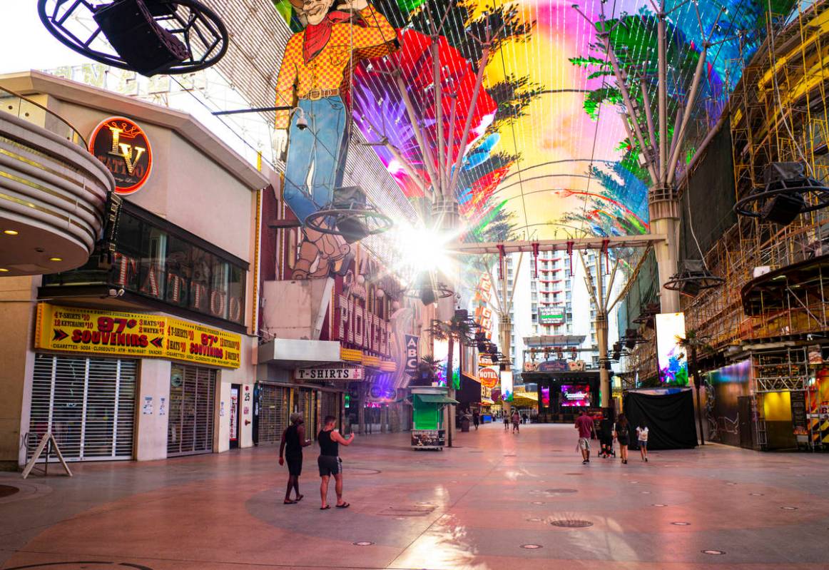 People walk around the Fremont Street Experience as hotel-casinos reopen in downtown Las Vegas ...