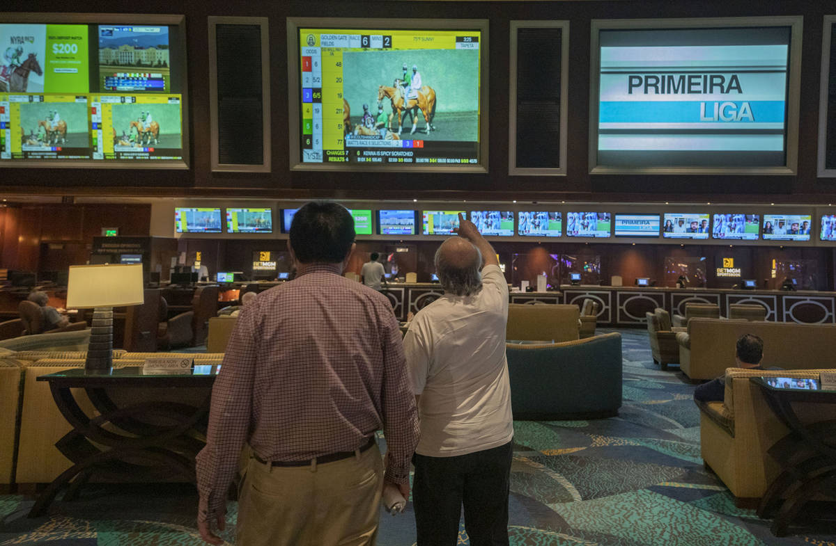 Individuals wait for a horse race to begin during the reopening of the Bellagio sportsbook, Thu ...