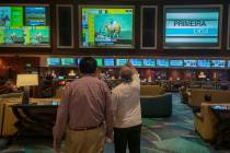 Individuals wait for a horse race to begin during the reopening of the Bellagio sportsbook, Thu ...
