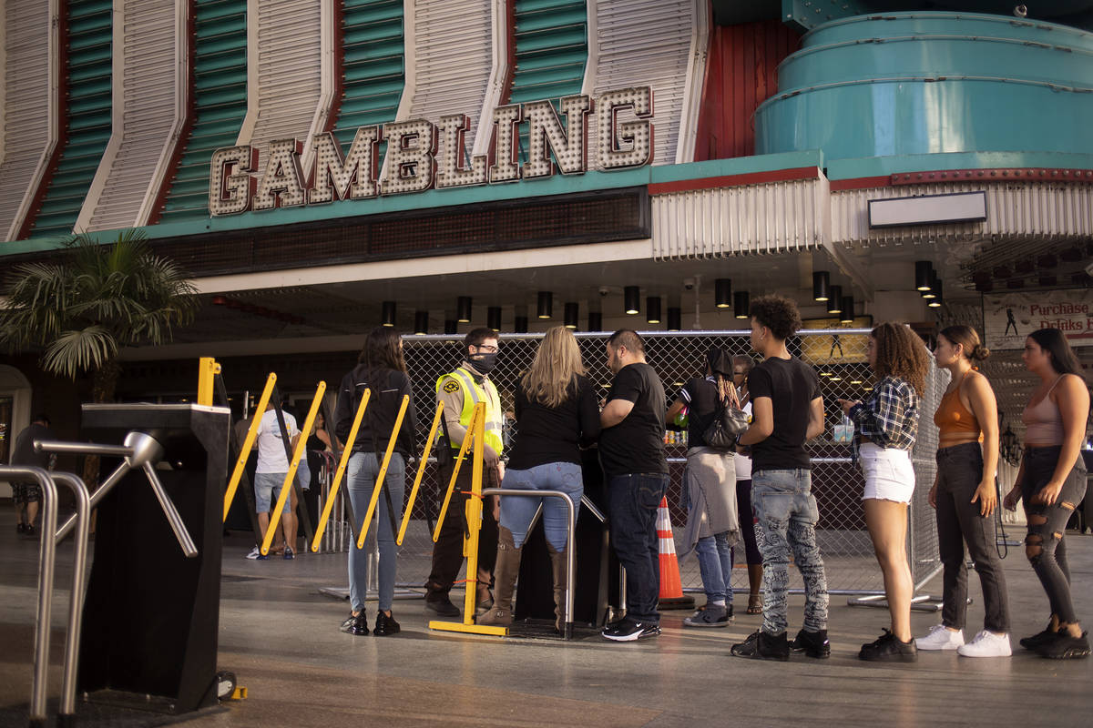 People wait in line to enter part of Fremont Street Experience in front of Binion's on Friday, ...