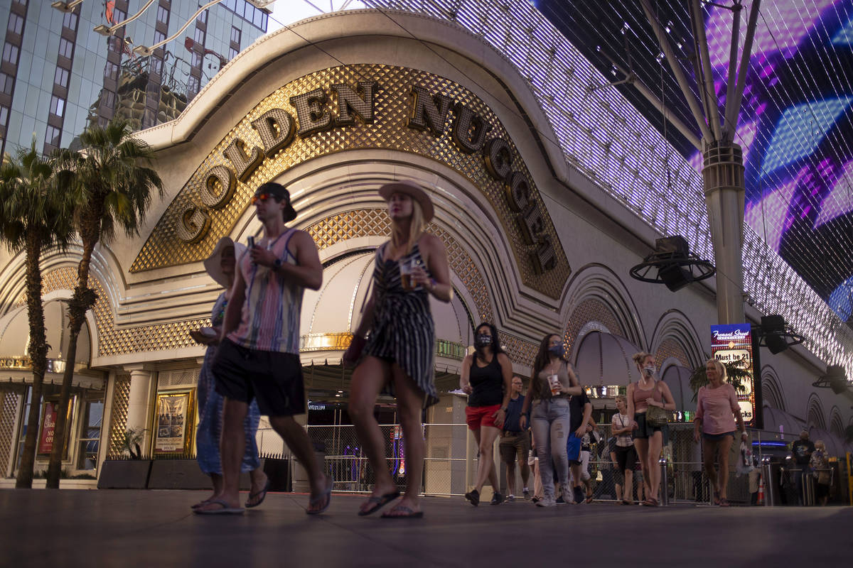 Pedestrians cross the street on Fremont Street Experience with Golden Nugget in the background ...