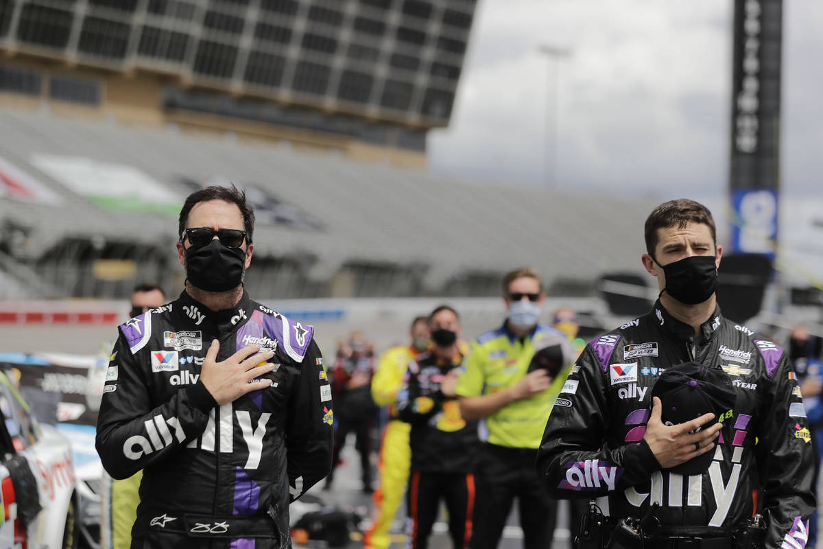 Jimmie Johnson, left, and crew members stand in pit row during the national anthem before a NAS ...