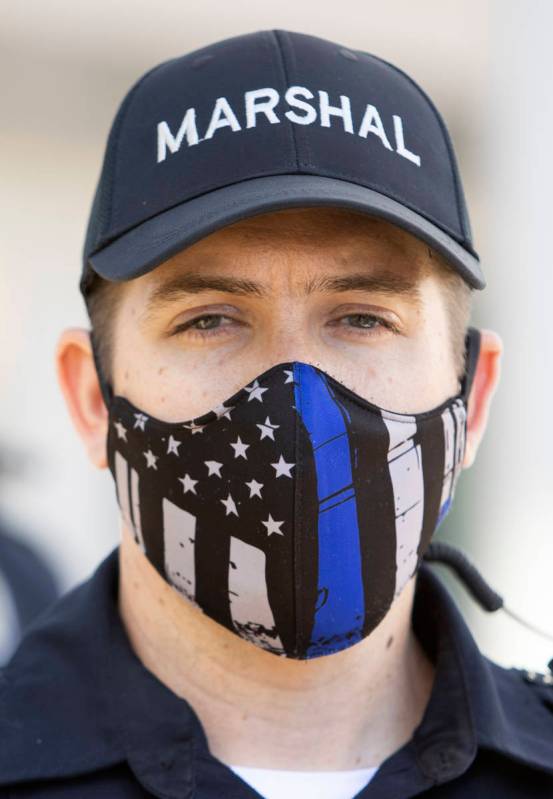 One Las Vegas police officer wears a "thin blue line" mask while standing between pro ...