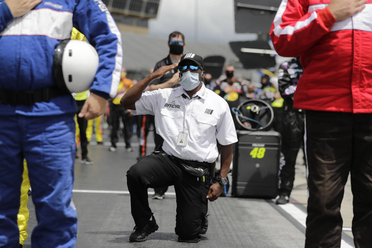 A NASCAR official kneels during the national anthem before a NASCAR Cup Series auto race at Atl ...