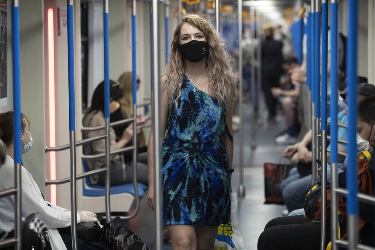 A woman wearing a face mask to protect against coronavirus walks in a carriage of a subway in M ...