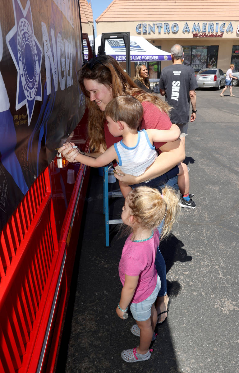 Yasmina Gimenez signs a banner with Orion Makarechian, 1, and Liyah Makarechian during a fundra ...