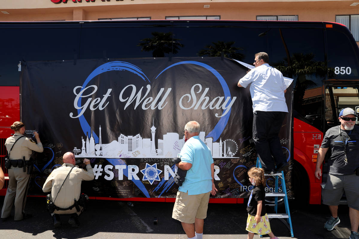 Las Vegas police officers Rae-Ann Armstrong and Brandon Heim sign a banner as coach operator Ti ...