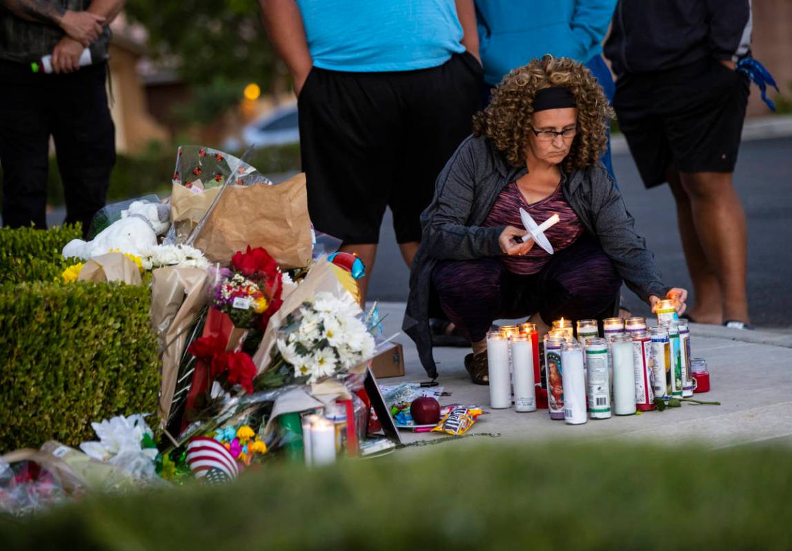 Marianne Littledike lights candles as people gather for a vigil in memory of David Cox, 18, and ...