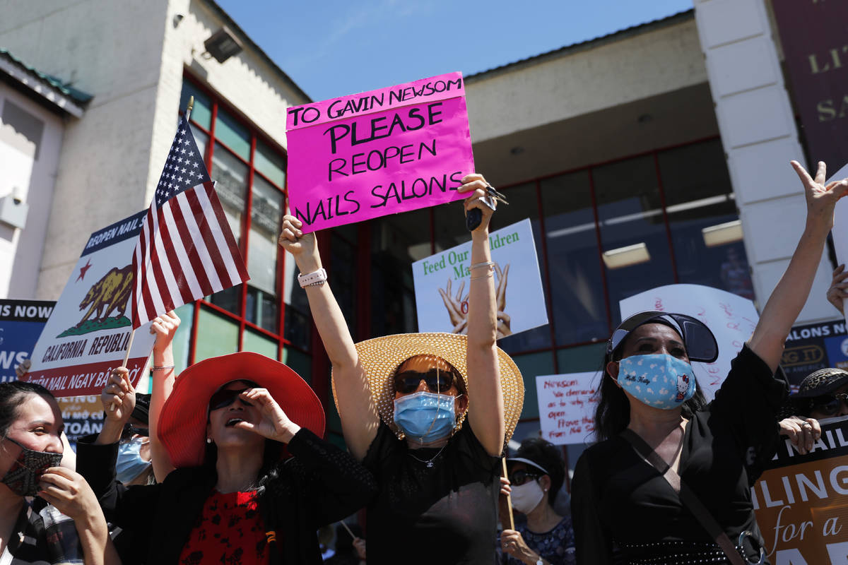 FILE - In this June 8, 2020, file photo nail shop owners and workers hold signs during a protes ...
