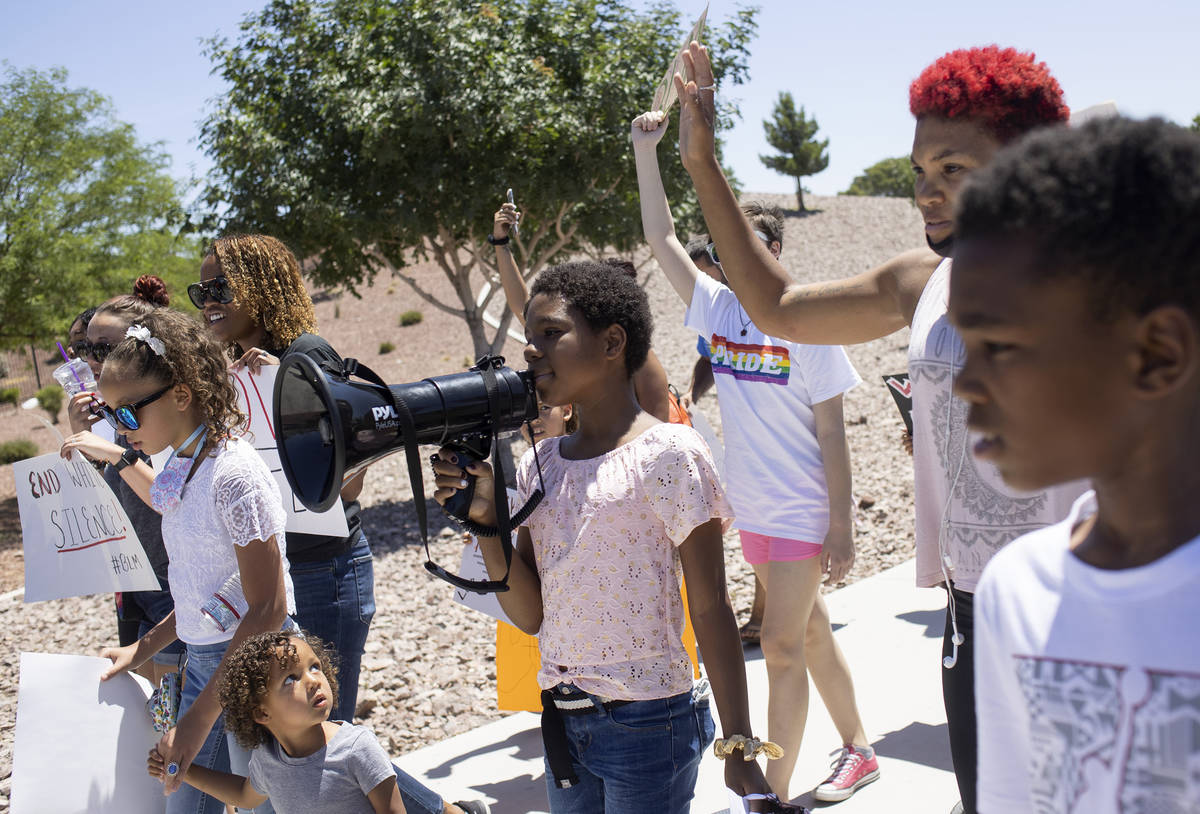 Chasadity Patterson-Hudson, center, 11, takes a turn on the megaphone to chant "no justice ...