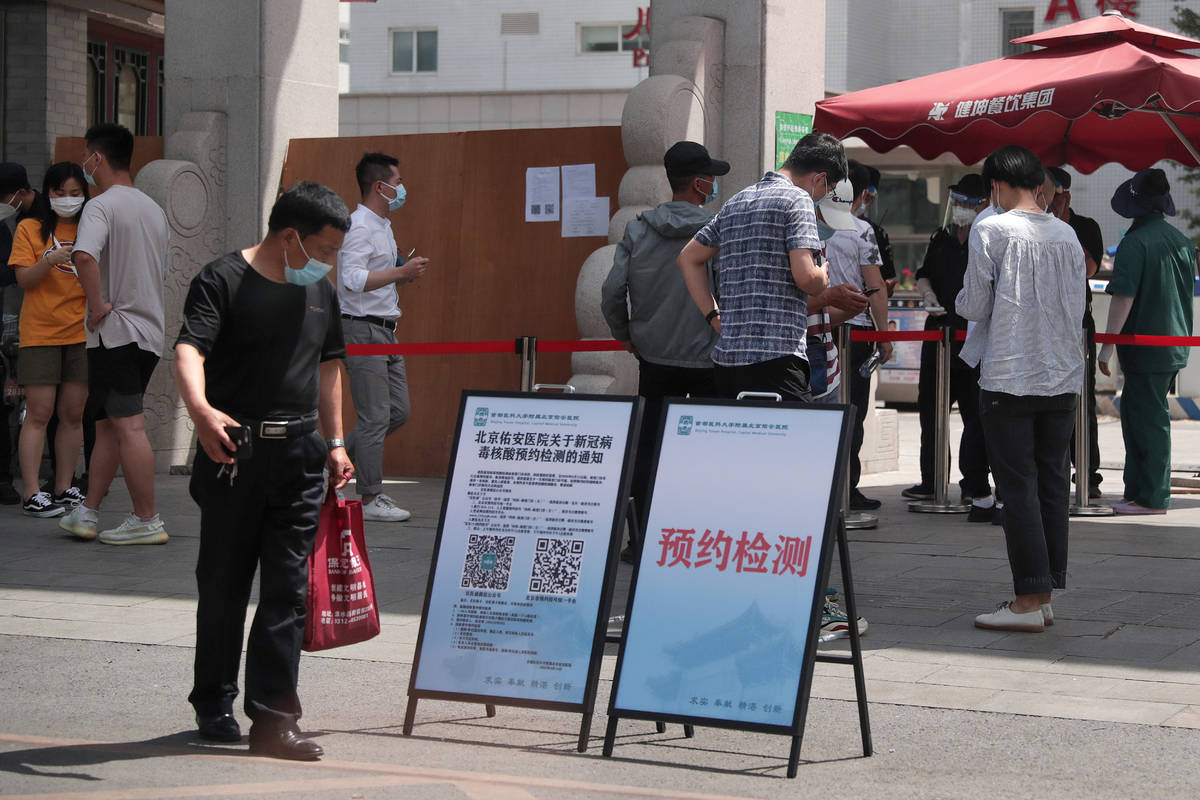 People wearing protective face masks to help curb the spread of the new coronavirus gather outs ...