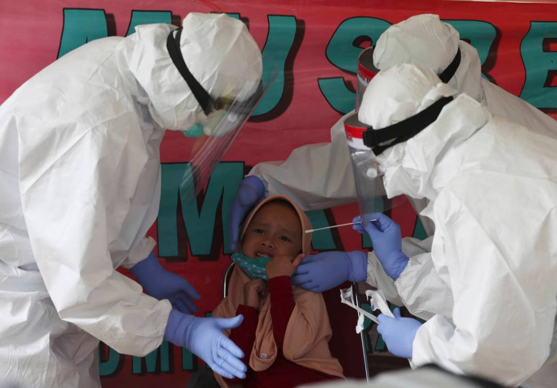 Health workers take a nasal swab sample from a girl during public testing for the new coronavir ...