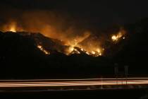Vehicle lights leave streaks a the Bighorn Fire moves along the western side of the Santa Catal ...