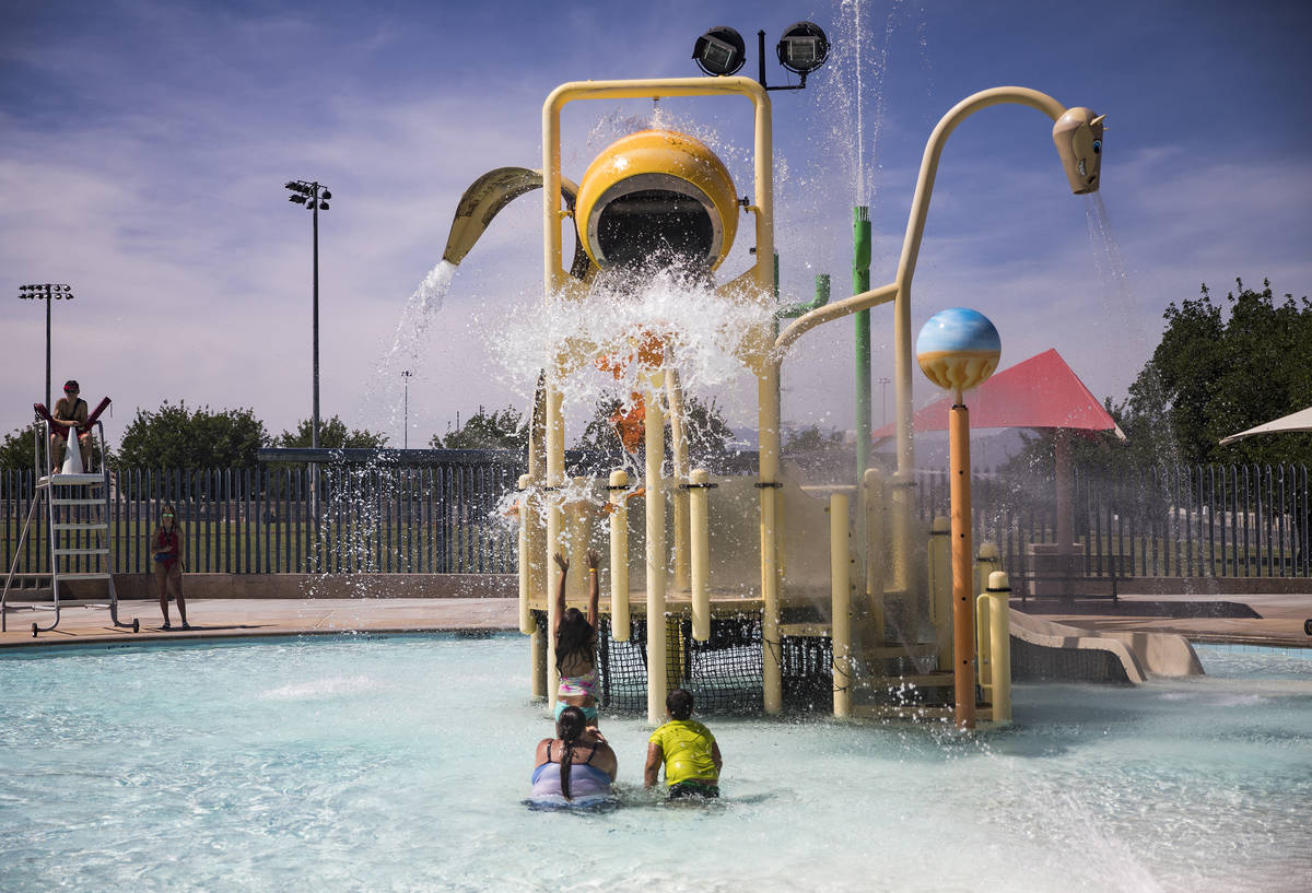 Swimmers await a bucket of water to fall from the water park at Garside Pool in Las Vegas, Mond ...