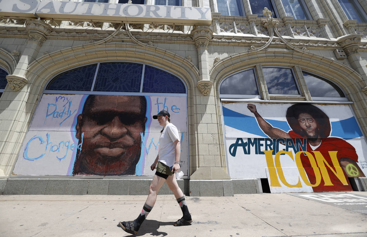 A pedestrian passes murals to honor George Floyd and former NFL quarterback Colin Kaepernick co ...