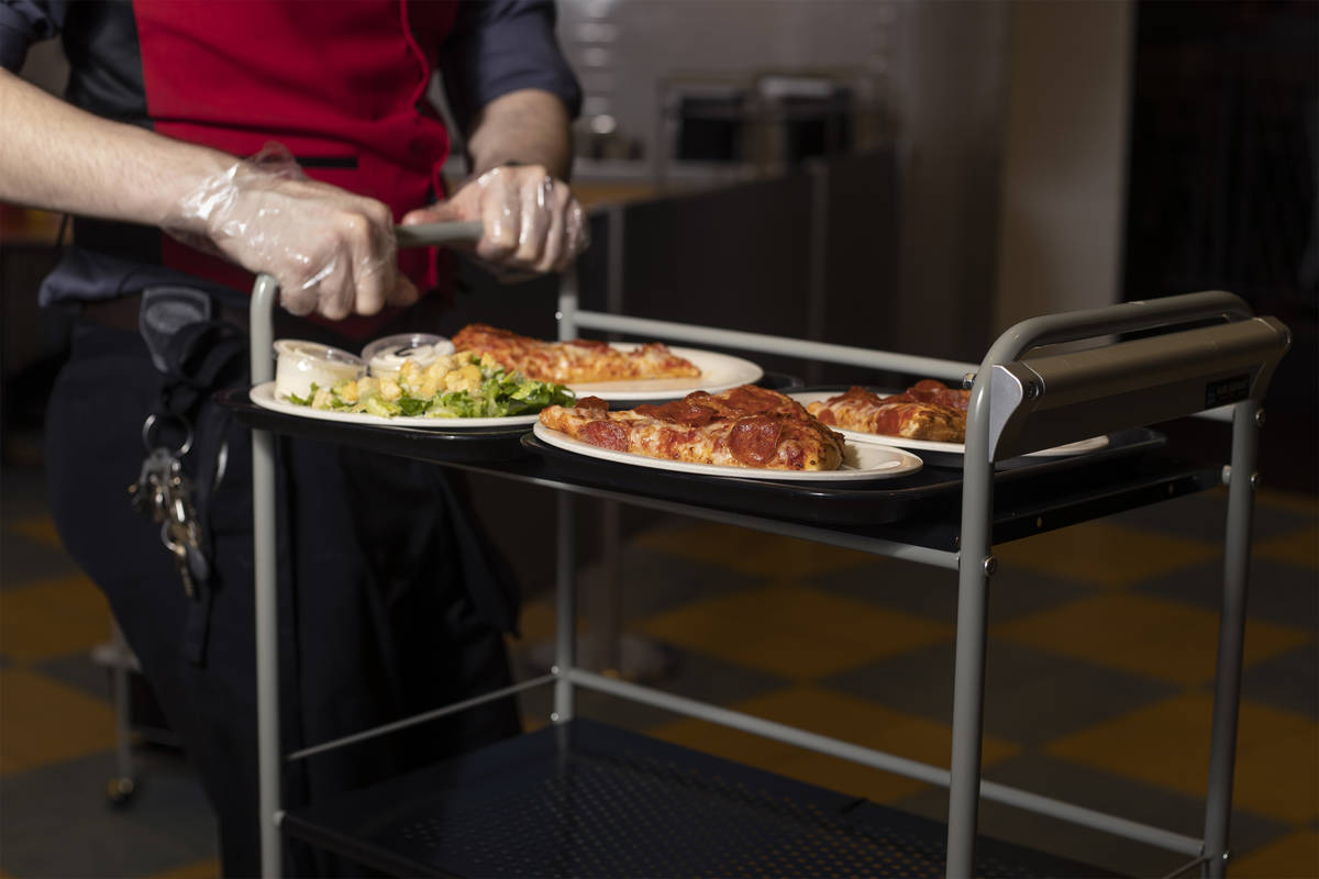 Servers and food runners bring food to tables to minimize coronavirus exposure at the buffet at ...