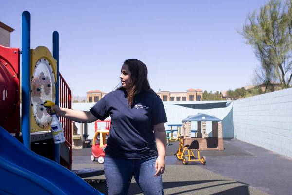 Miss Destaney sprays the playground with disinfectant after her class had outside time at Risin ...