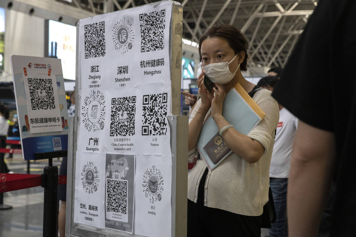 A passenger looks at a board with QR codes for health screening from different provinces at the ...