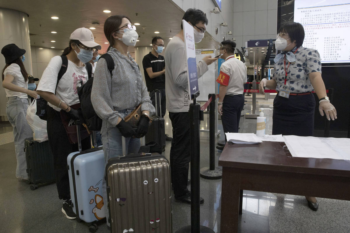 Travelers make enquiries at a checkpoint for passengers from high risk areas to present their C ...