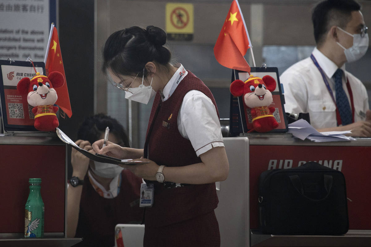 Airline employees work at a check-in counter at the Beijing Capital Airport terminal 3 in Beiji ...