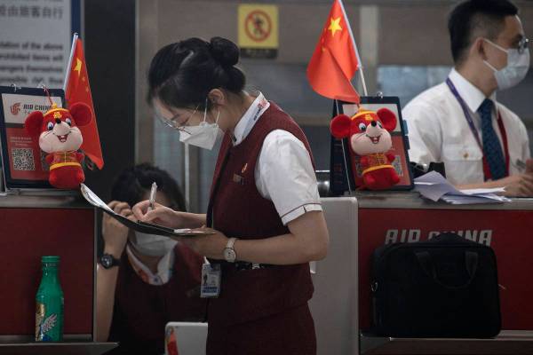 Airline employees work at a check-in counter at the Beijing Capital Airport terminal 3 in Beiji ...