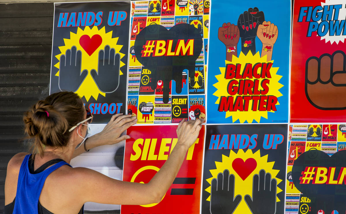 Cynthia Hartness attaches one of about 180 BLM posters to the facade of the Majestic Repertory ...