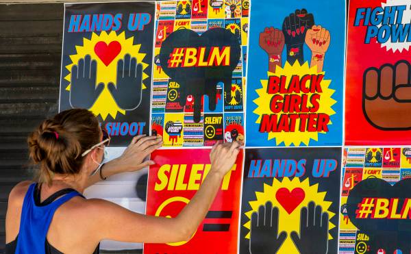 Cynthia Hartness attaches one of about 180 BLM posters to the facade of the Majestic Repertory ...