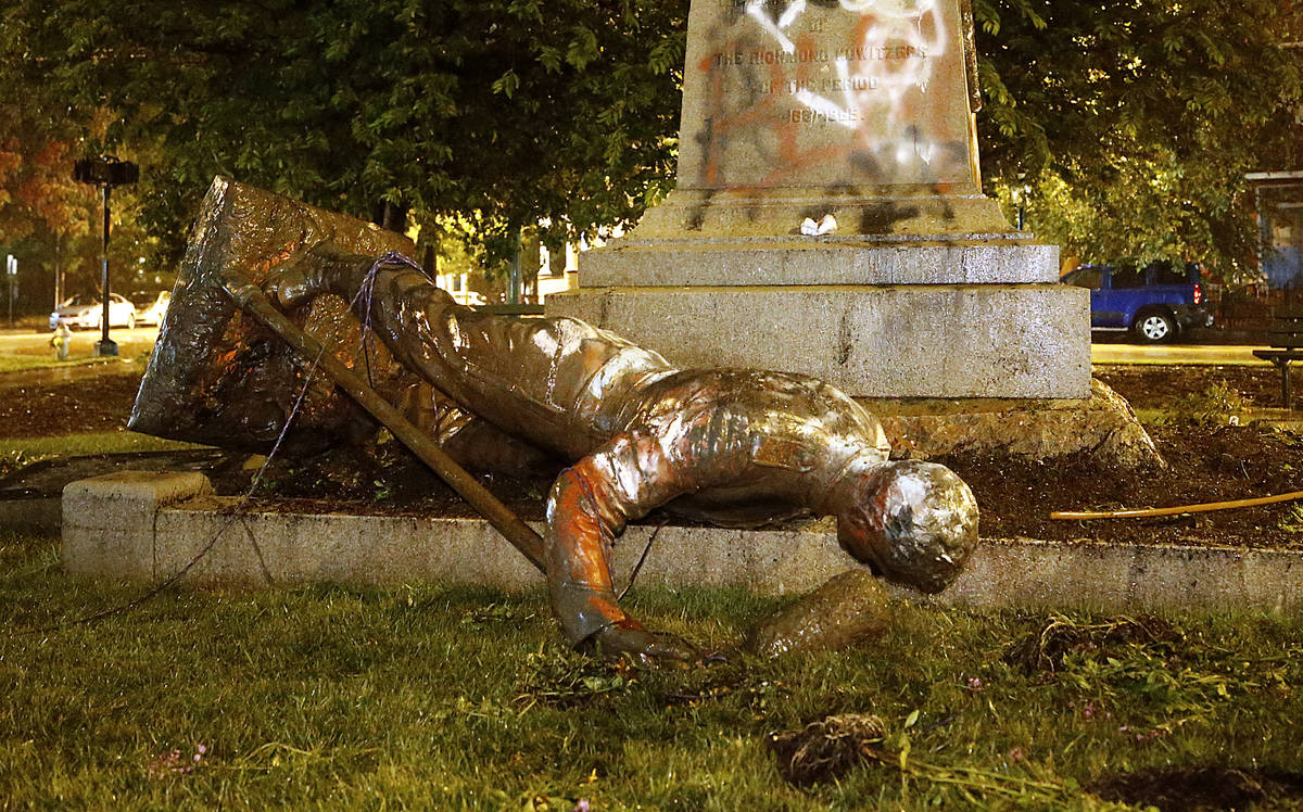 A statue from the Richmond Howitzers Monument in Richmond, Va., lies after being toppled Tuesda ...