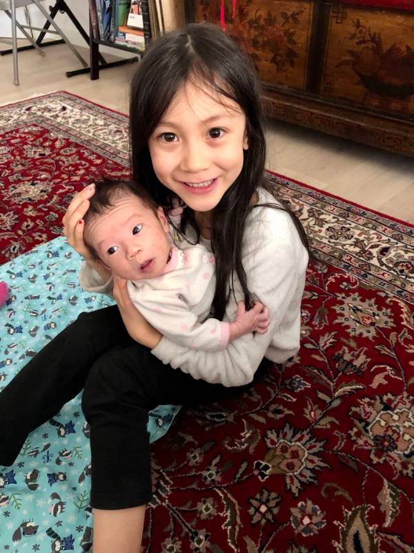 Lorelai Stein, 7, holds her newborn baby sister, Sadie. Sadie was born at home April 1 in Madri ...
