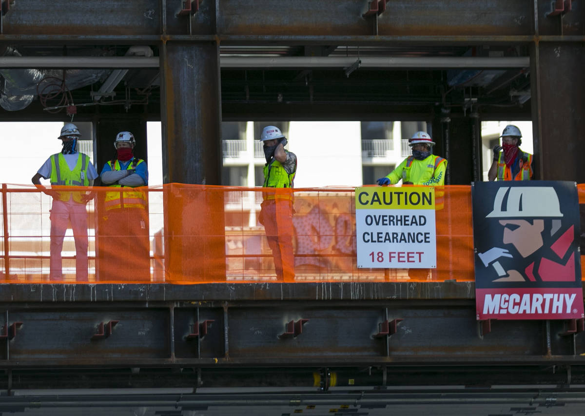 Workers watch as the last steel beam, signed by Derek Stevens, CEO and developer of Circa Resor ...