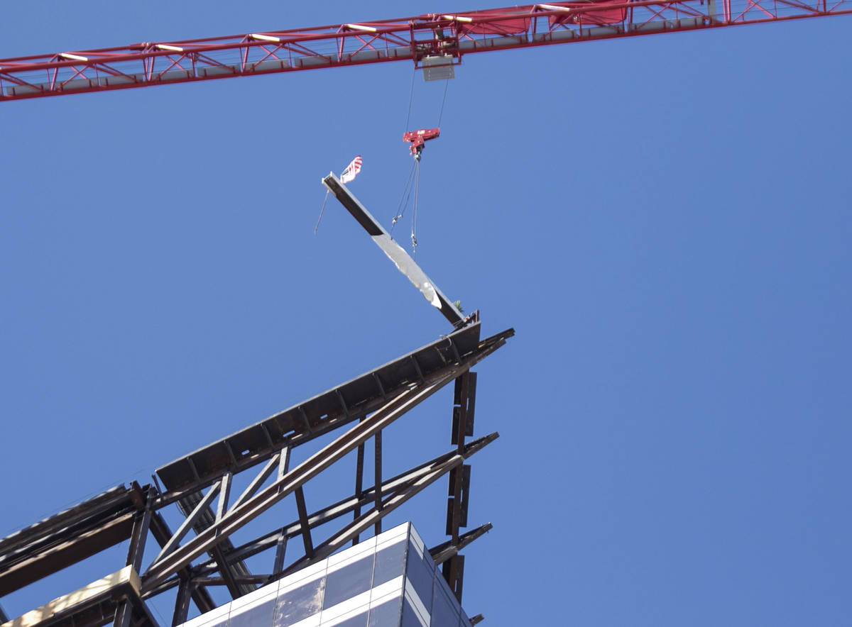 Workers hoist the last steel beam signed by Derek Stevens, CEO and developer of Circa Resort a ...