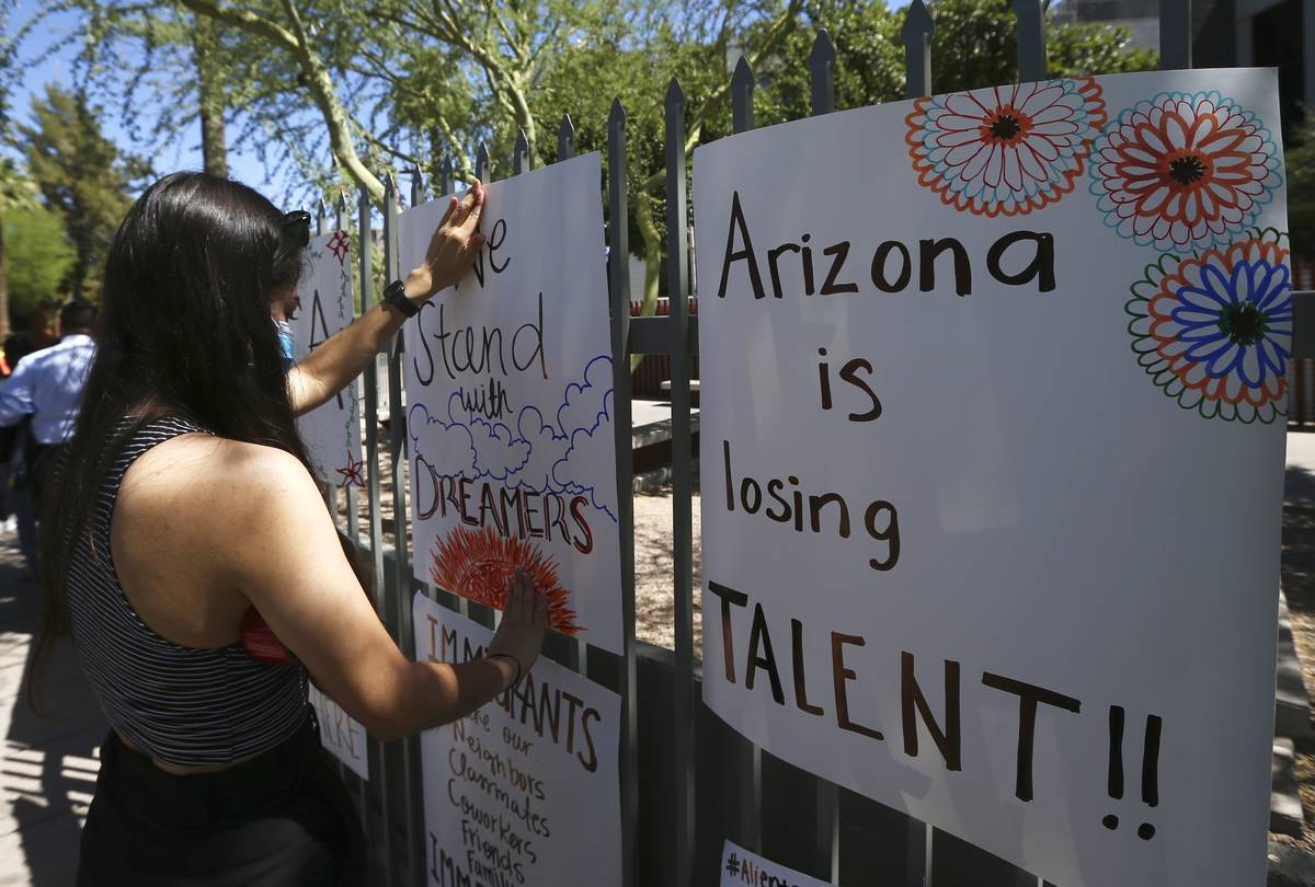 Deya Garcia, Deferred Action for Childhood Arrivals recipient, tapes up a poster in front of th ...