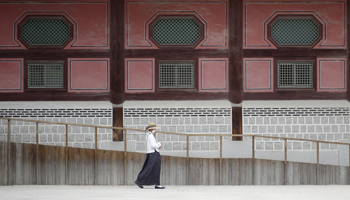 A woman wearing a face mask walks outside of Heungnyemun gate of the 14th-century Gyeongbok Pal ...