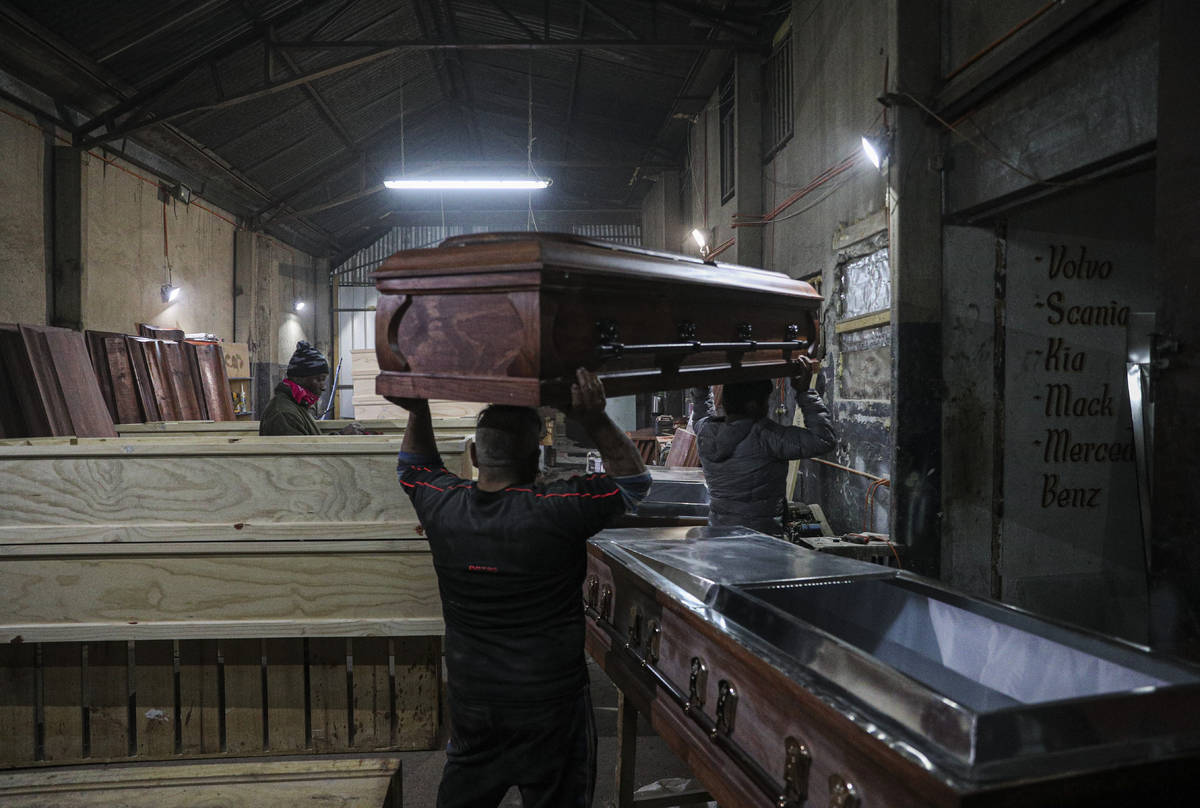 Cesar Ambrosio helps his father carry a coffin at the Bergut Funeral Services factory in Santia ...
