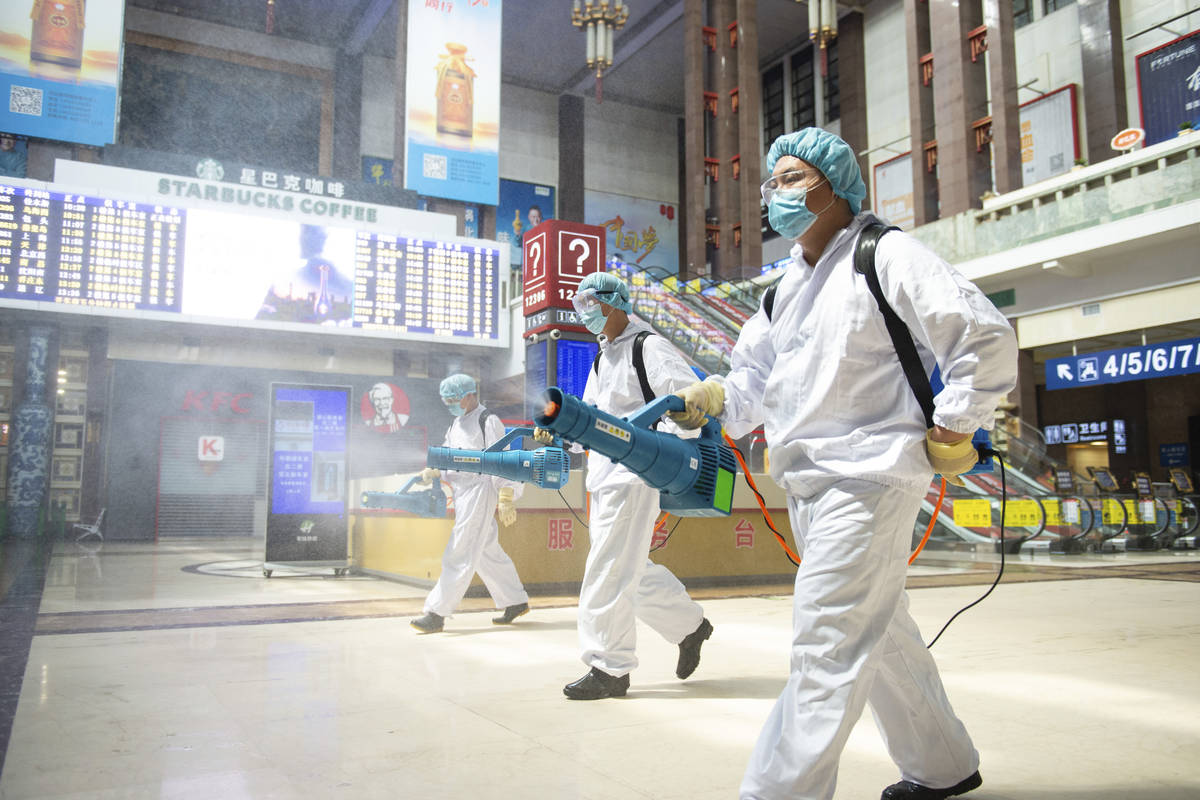 In this June 18, 2020, photo released by China's Xinhua News Agency, workers spray disinfectant ...