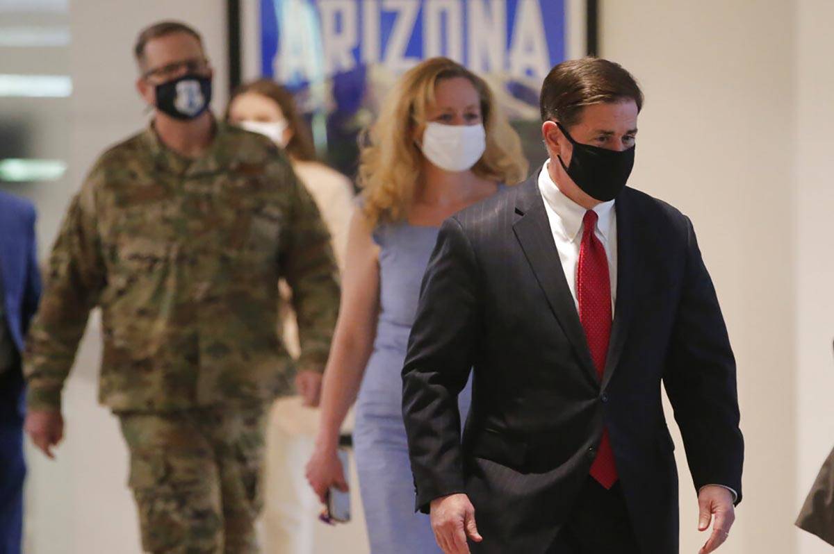 Arizona Gov. Doug Ducey, right, arrives to give an update on COVID-19 in Arizona during a news ...