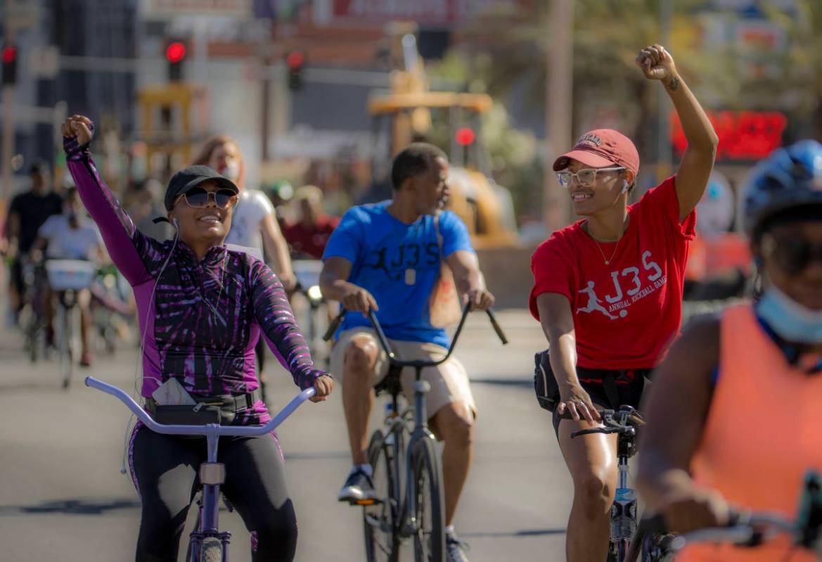 Participants in a Black Lives Matter bike ride against injustice show their support while passi ...