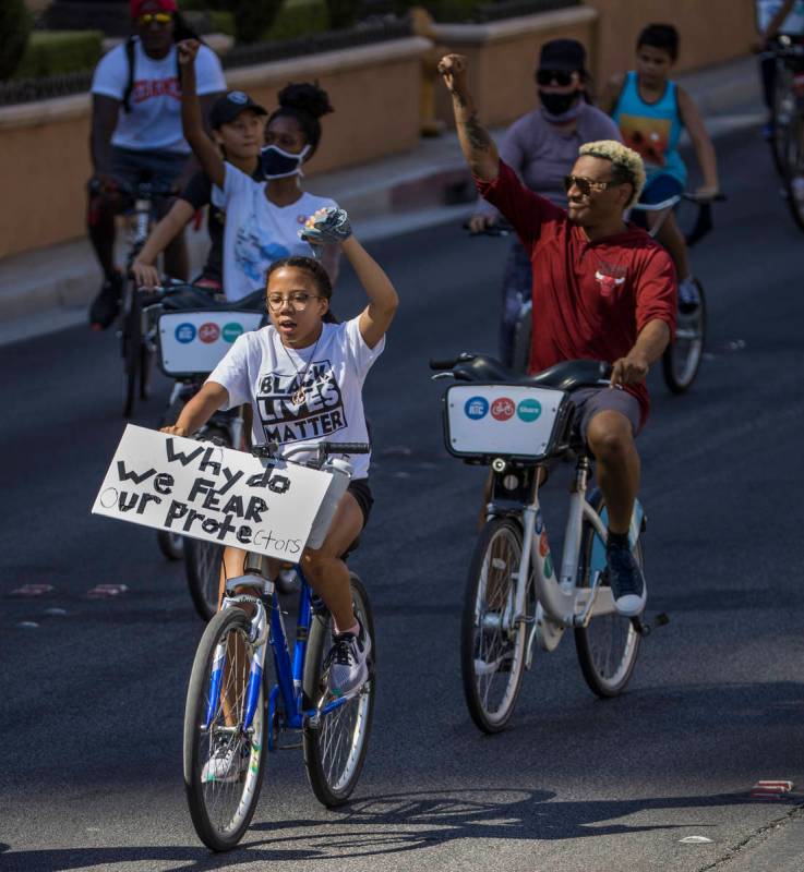 Participants in a Black Lives Matter bike ride against injustice show their support while passi ...