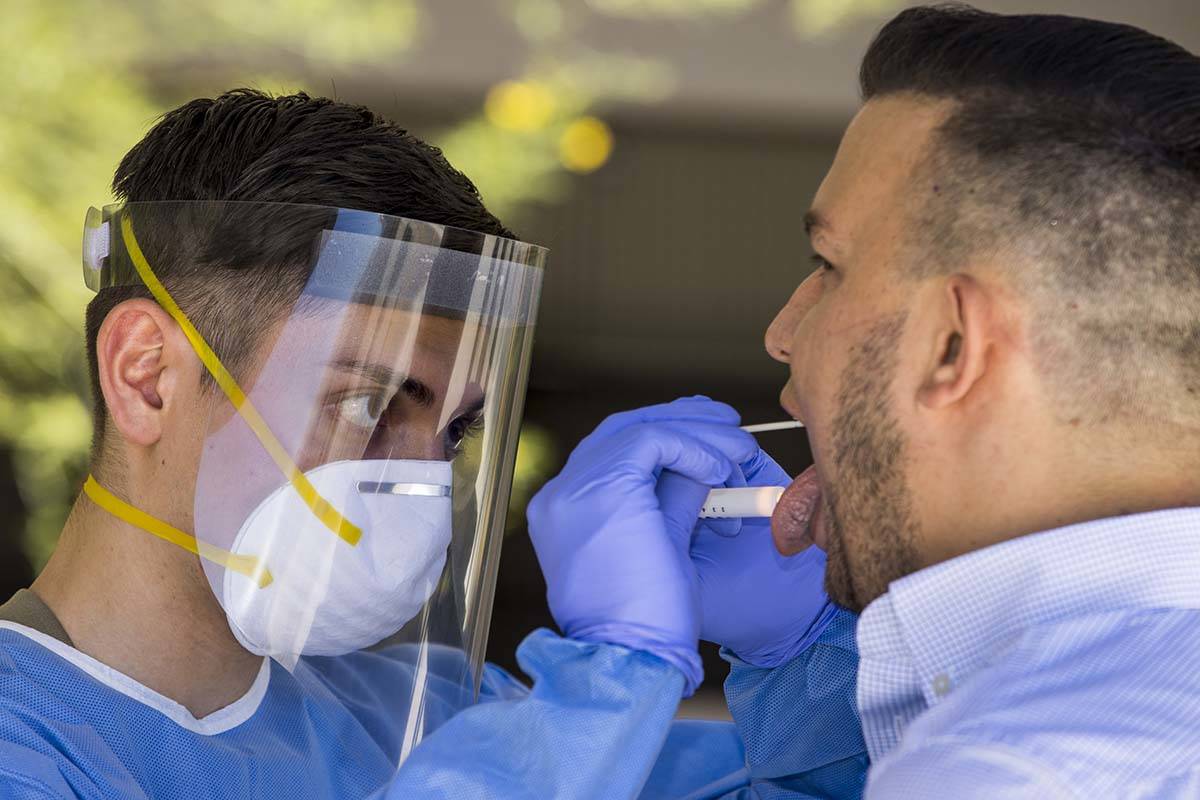 Nevada National Guard soldier PFC Nikolas Herrera, left, inserts a swab into the mouth of Paulo ...