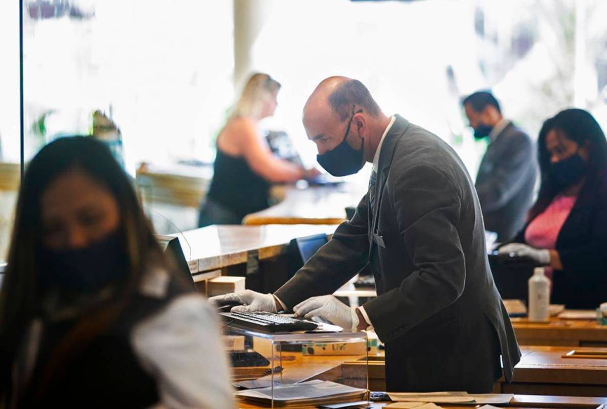 Guest service representatives wear protective masks and gloves while checking people in at TI o ...