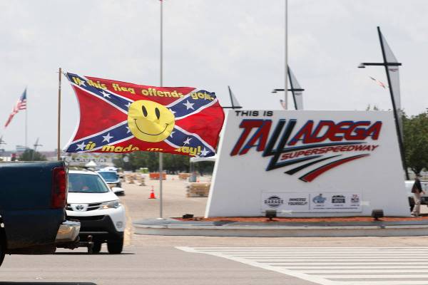 Race fans fly Confederate battle flags and United States flags as they drive by the entrance to ...