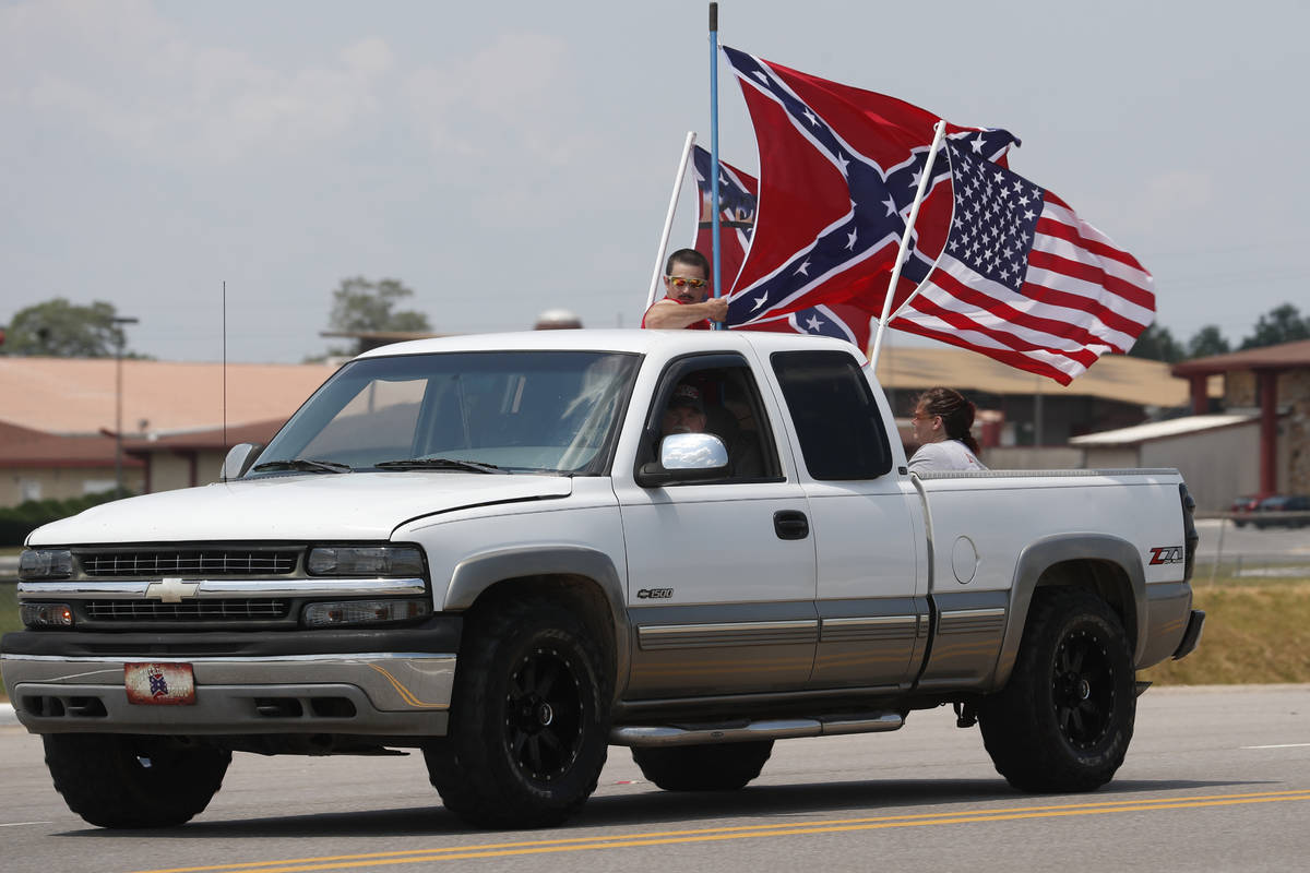 Race fans fly Confederate battle flags and a United States flag as they drive by Talladega Supe ...