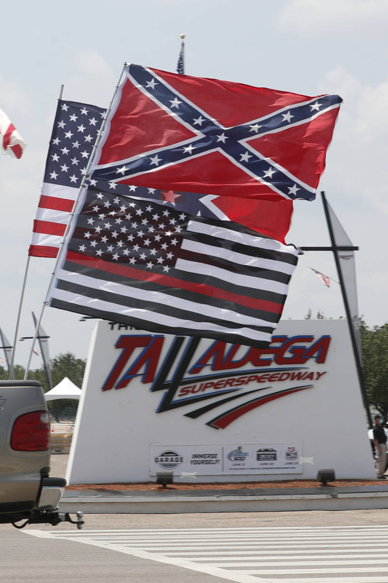 Race fans fly Confederate battle flags and United States flags as they drive by the entrance to ...