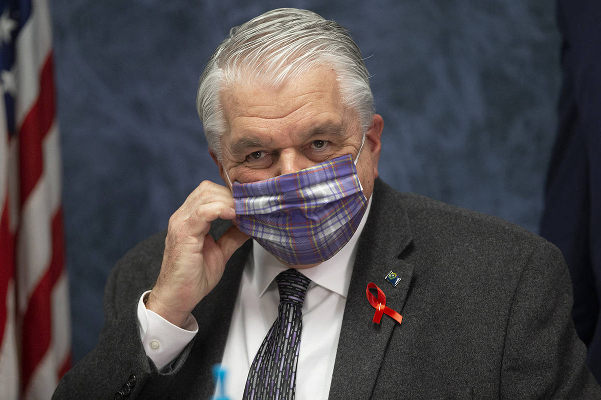 Gov. Steve Sisolak wears a protective mask before the start of a press conference to update Nev ...