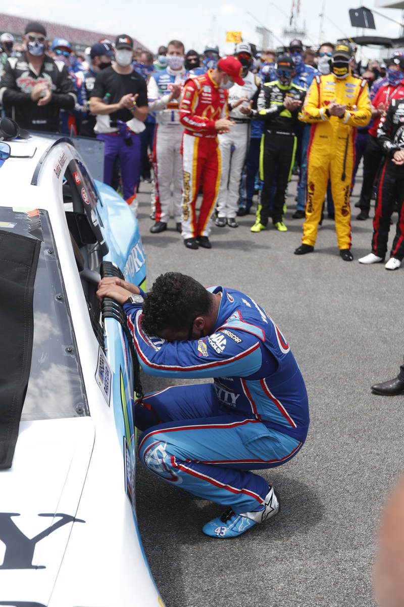 Driver Bubba Wallace, front, is overcome with emotion as he arrives at his car in the pits of t ...