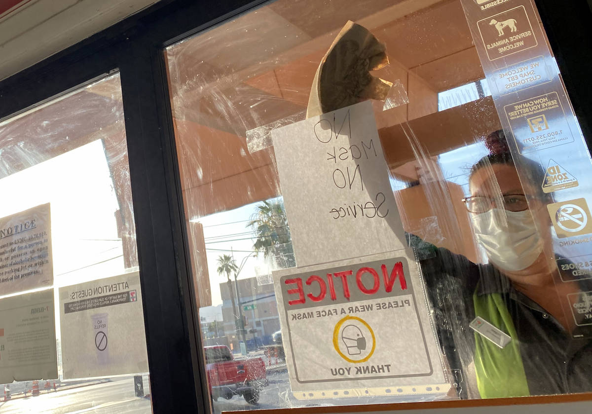 A clerk washes a window with a "No Mask No Service" sign at 7-Eleven on Las Vegas Boulevard at ...