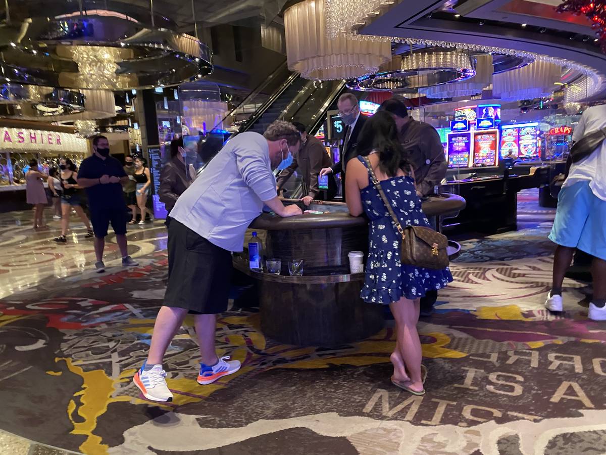 Players and staff wear masks at a table game at the Cosmopolitan Saturday, June 27, 2020. (Las ...