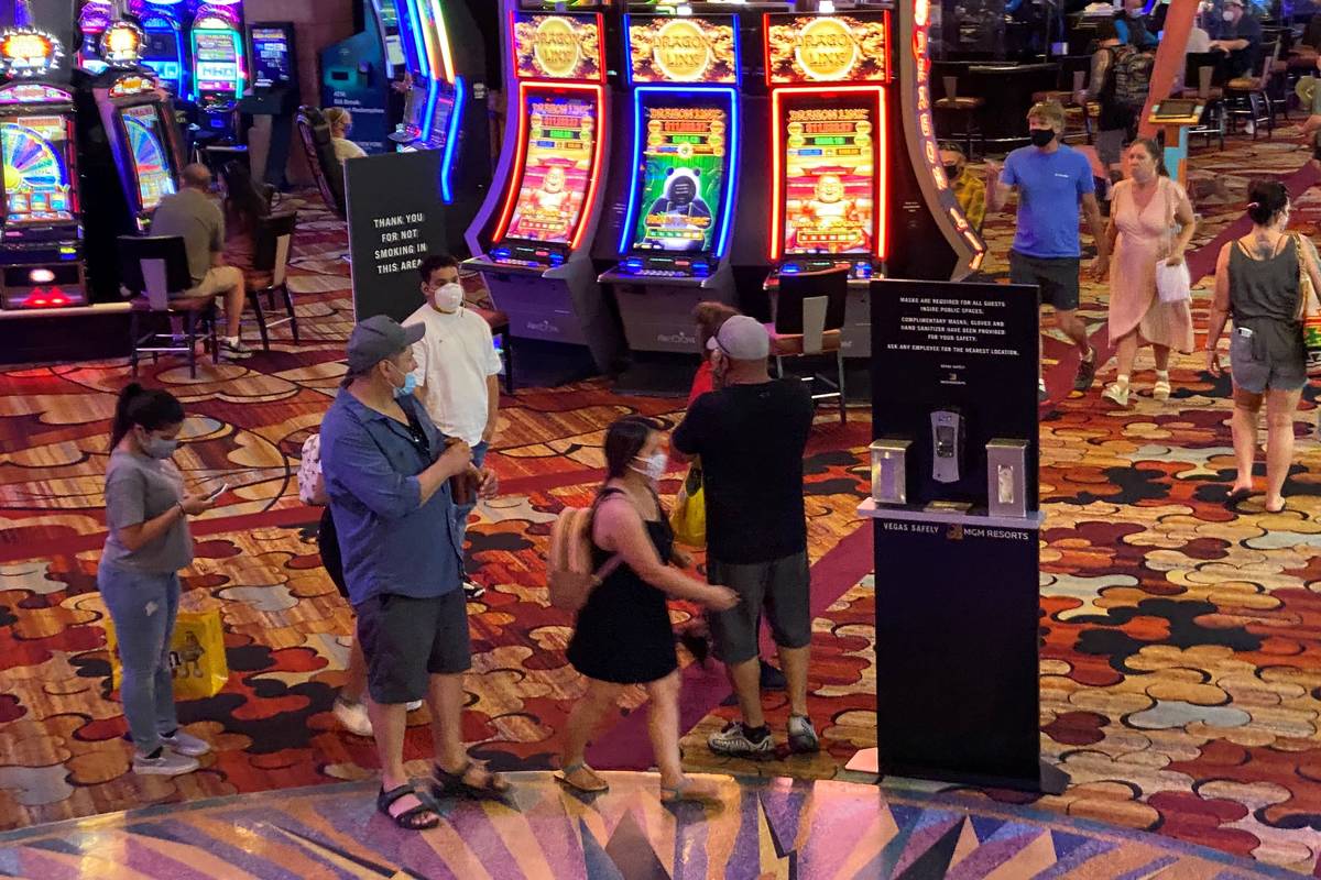 A group of patrons at the New York-New York wear masks on the casino floor near a hand sanitize ...