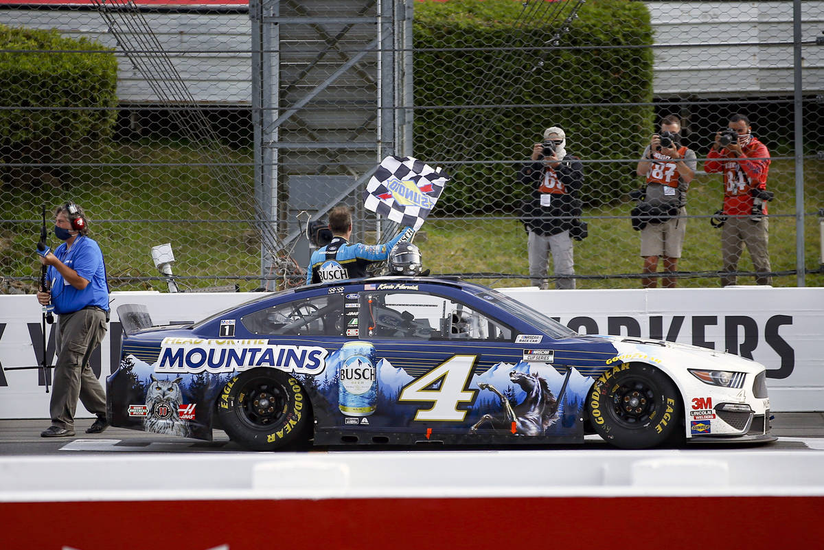 Kevin Harvick waves a checker flag for photographers after winning the NASCAR Cup Series auto r ...