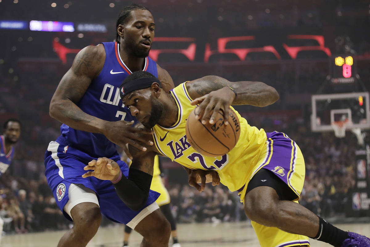 Los Angeles Lakers' LeBron James, right, is defended by Los Angeles Clippers' Kawhi Leonard dur ...